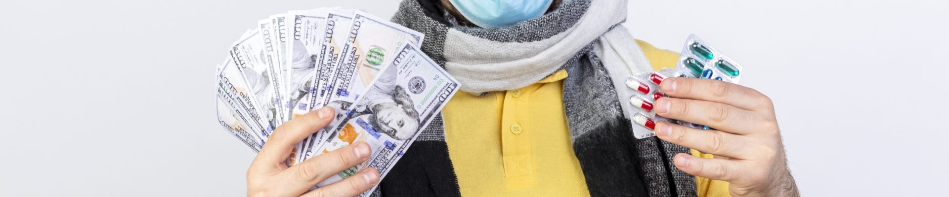 shocked young blonde ill slavic man wearing medical mask and scarf holds money and packs of medical pills isolated on white background with copy space